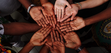 Palms up hands of happy group of multinational African, latin american and european people which stay together in circle