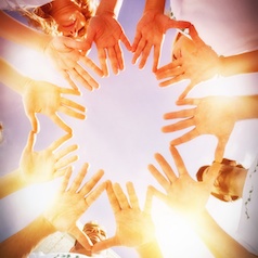 Volunteers with hands together against blue sky