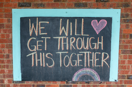 Chalk sign saying we will get through this together on a brick wall. Written during the Coronavirus pandemic lockdown.