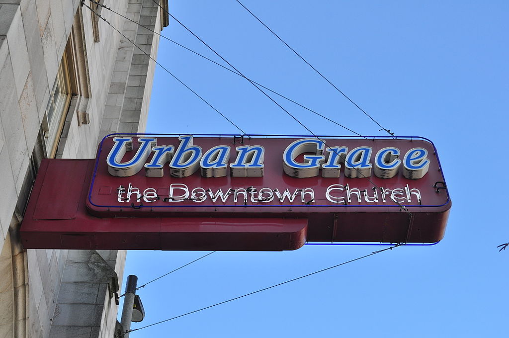 Photo of a neon sign that reads "Urban Grace, the Downtown church" on a gothic style church building.