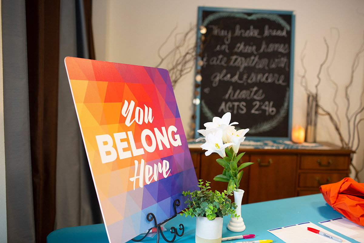 Photo of a sign that reads "You belong here" on a church sign-in table.