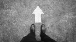 Businessman in black shoes standing at forward direction sign. Business path to success concept.