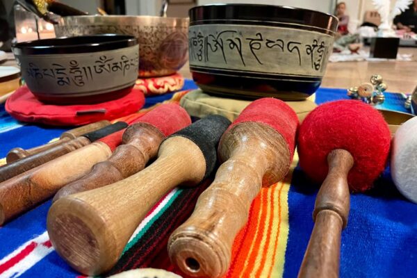 Photo of singing bowls and their mallets on a latin-american tapestry, with church members sitting in the background.