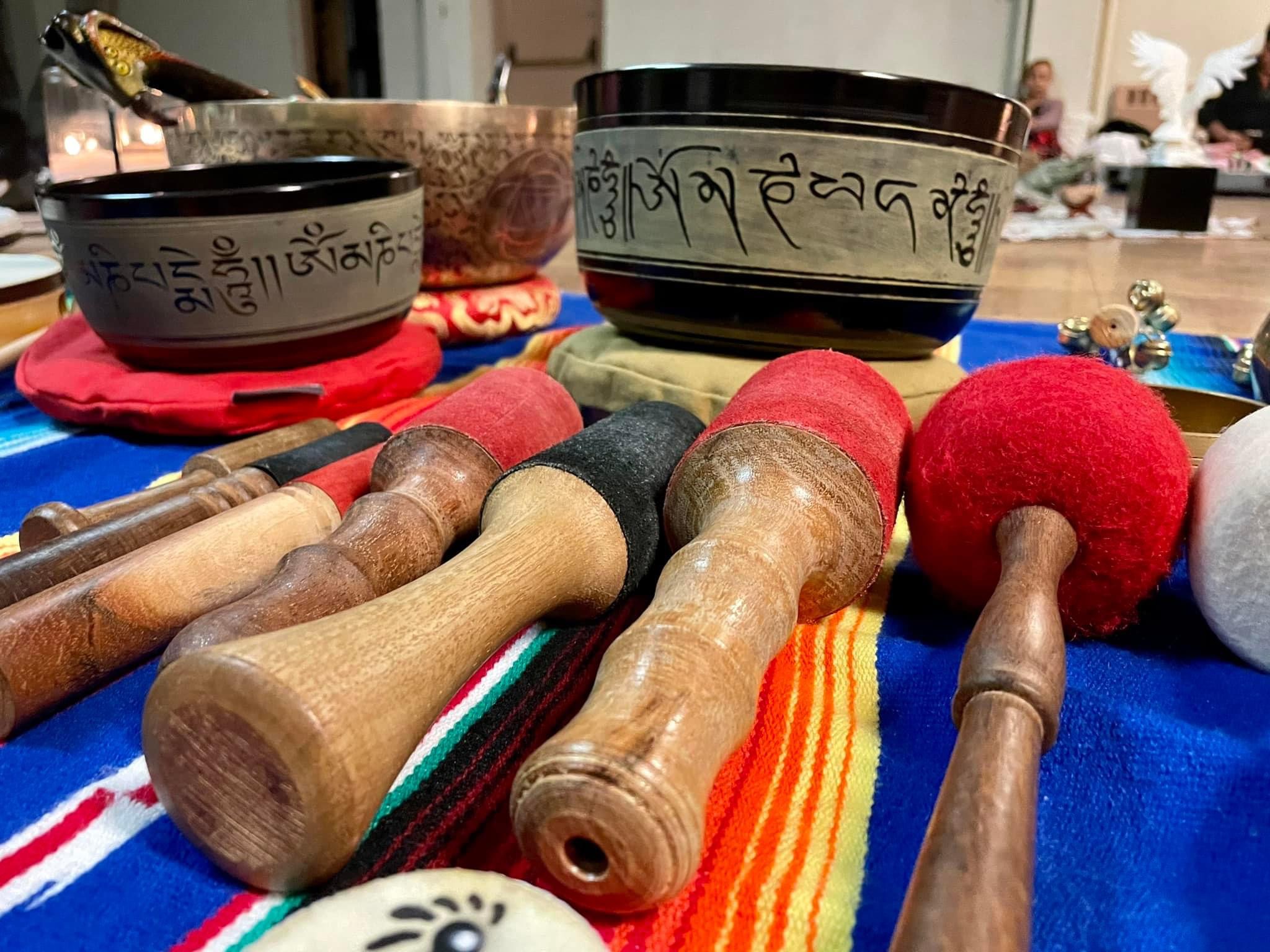 Photo of singing bowls and their mallets on a latin-american tapestry, with church members sitting in the background.