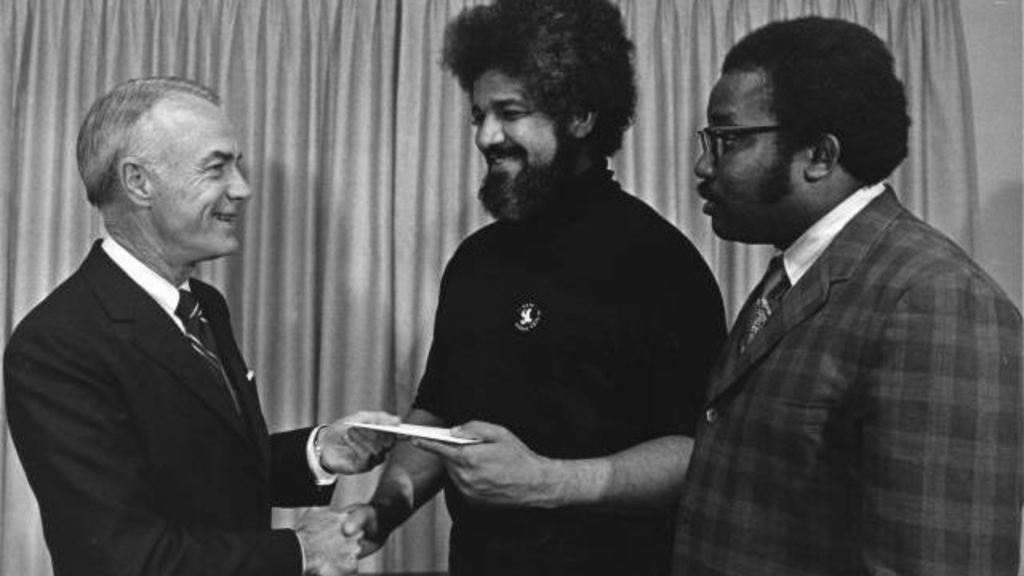 Thomas H. Lake (left), presents a donation to Father Boniface Hardin (center).